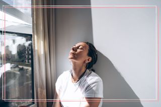 A woman relaxing next to a window