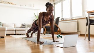 Woman doing press up exercise on yoga mat in living room