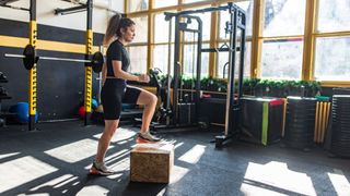 Woman stepping up onto box in the gym