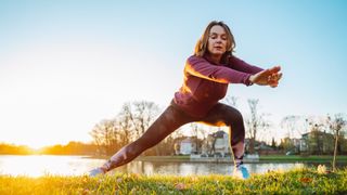 Woman doing sideways lunge in park wearing workout clothes