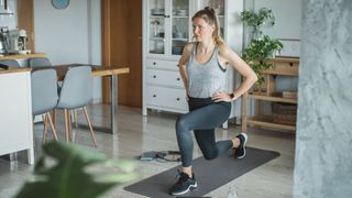 Woman doing backwards lunge in living room on yoga mat