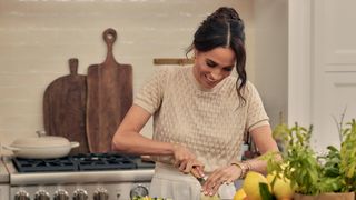 Meghan, Duchess of Sussex cuts a lemon with a Le Creuset dish in the background in episode 102 of With Love, Meghan