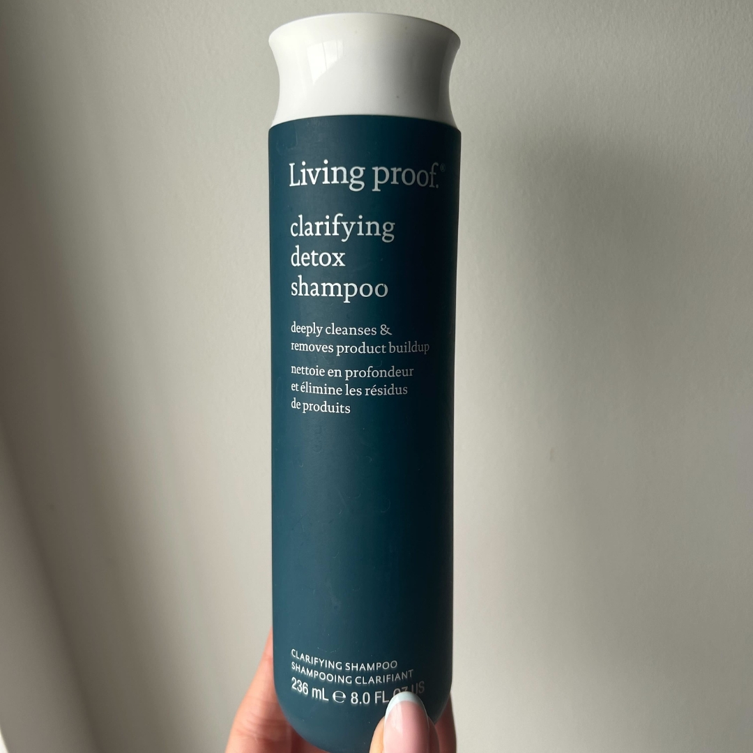 Hand holding Living Proof Clarifying Detox Shampoo with pastel blue French tip almond nails
