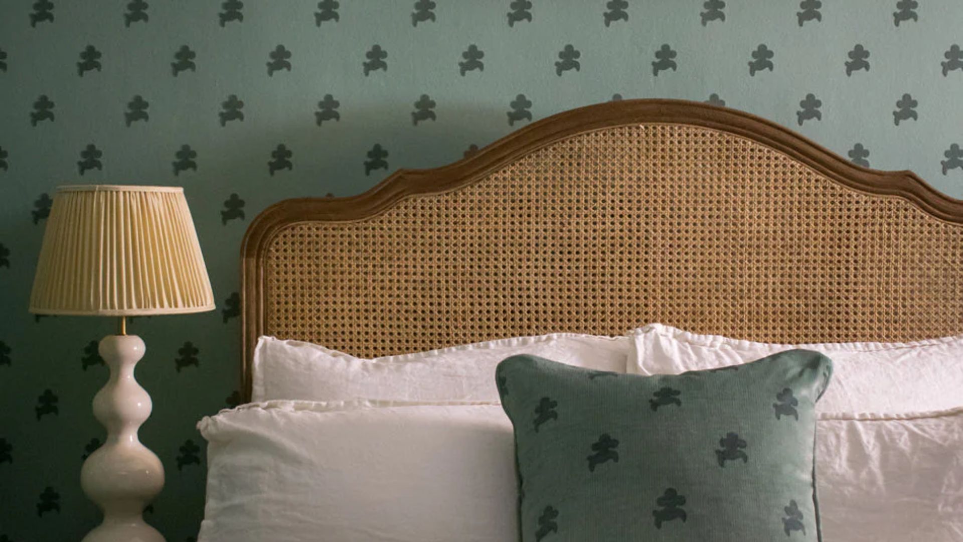 A bed in front of pistachio green wallpaper by Divine Savages