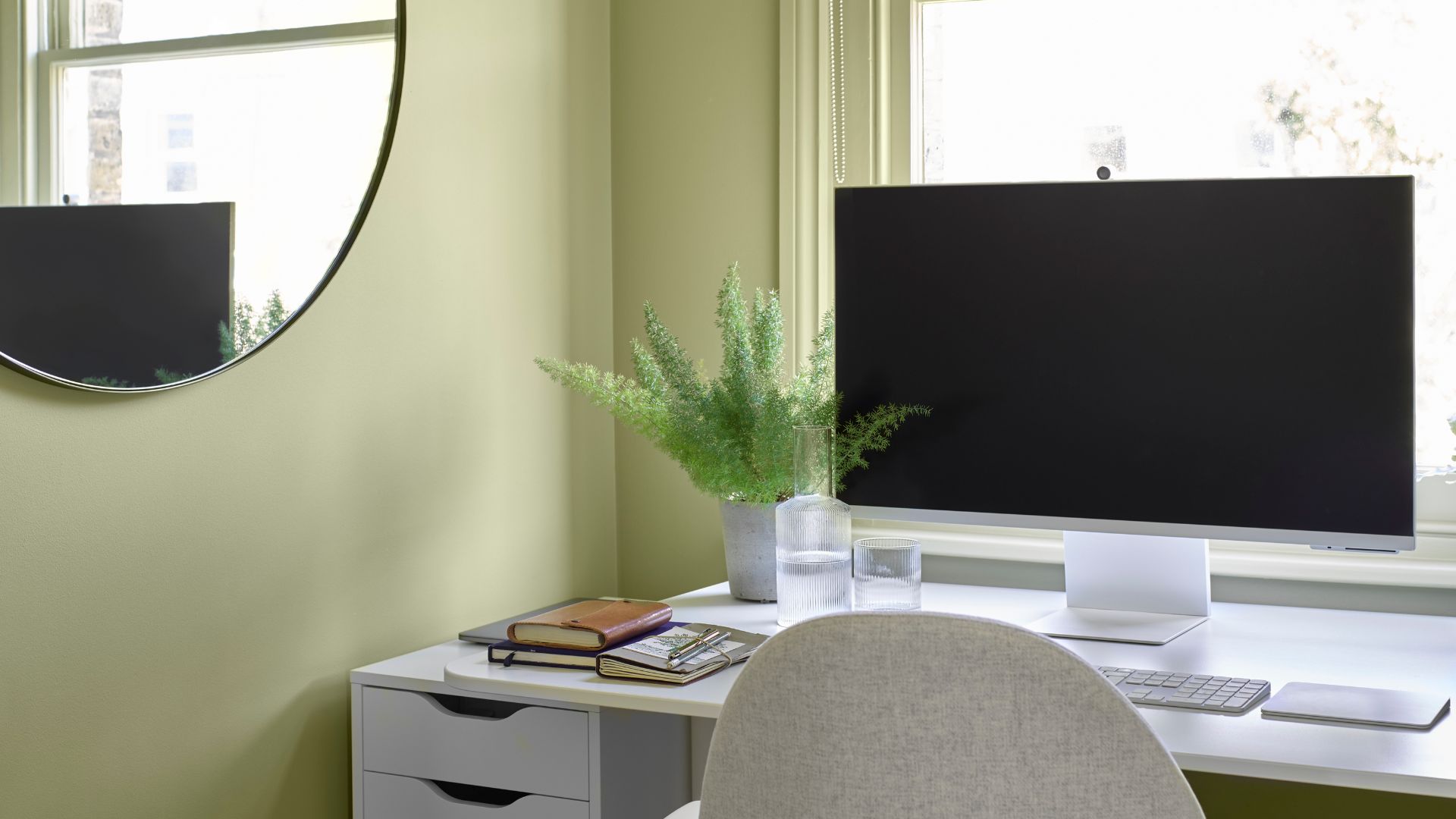 A small home office painted in pistachio with a laptop on a desk