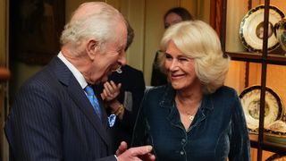 King Charles and Queen Camilla smile at each other during a reception to mark the launch of the Queen's reading room medal at Clarence House on March 25, 2025