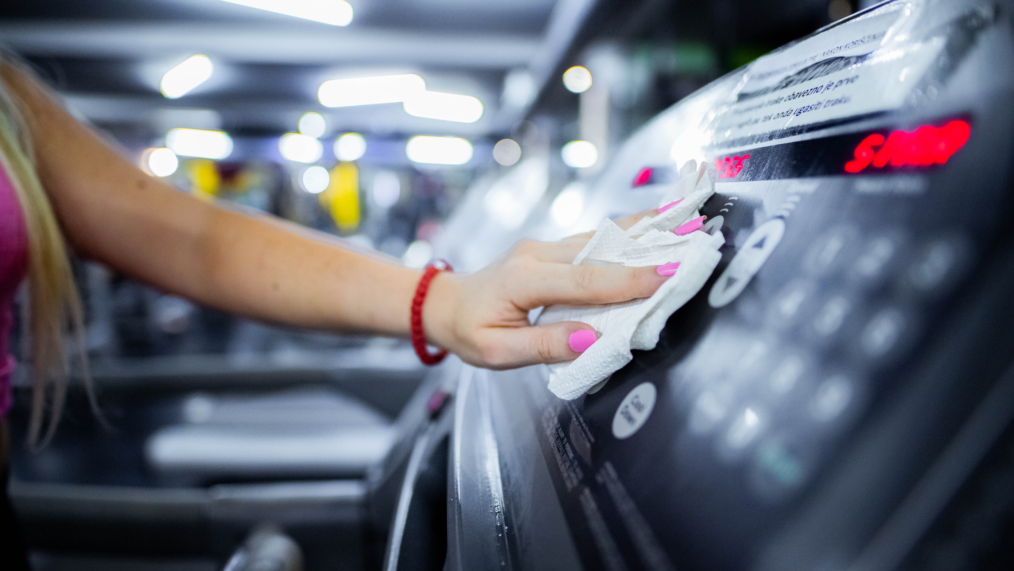 woman wiping treadmill with anti-bac wipe