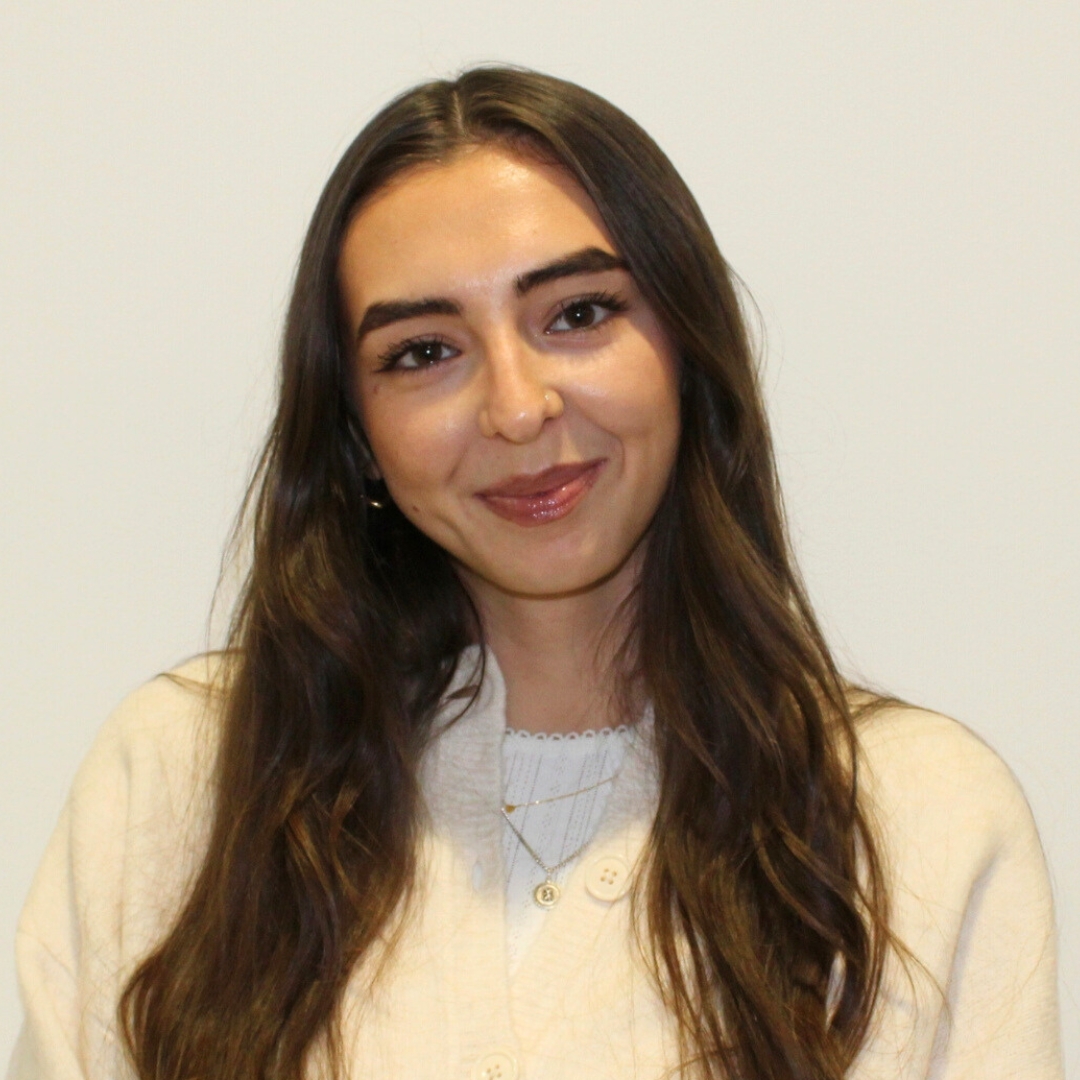 Image of Sennen Prickett, Digital Beauty Writer, smiling with curled long brunette hair