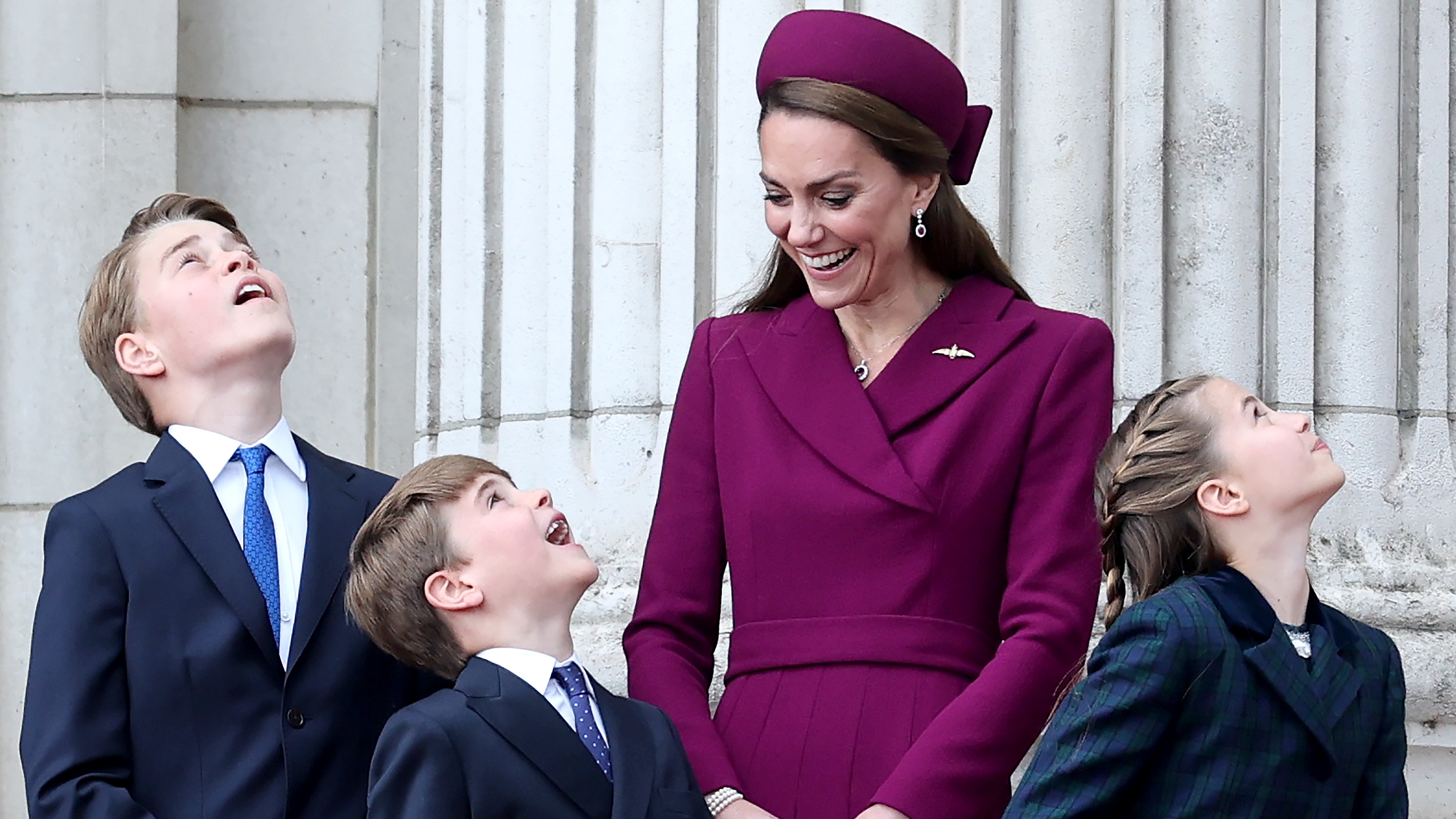 Prince George, Prince Louis and Princess Charlotte gaze at the sky, watched by the Princess of Wales, as they view the fly-past on the balcony of Buckingham Palace