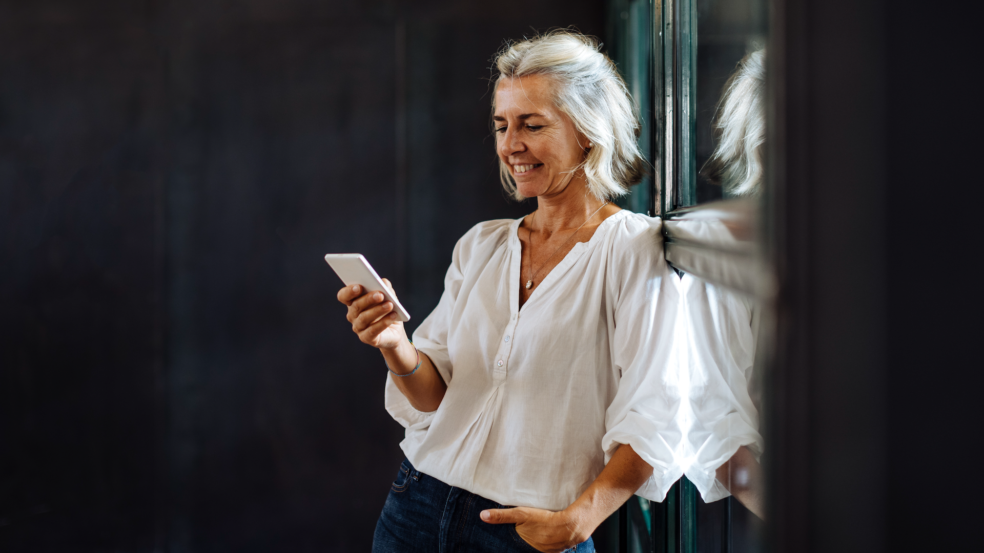 Woman leaning on wall while looking at phone