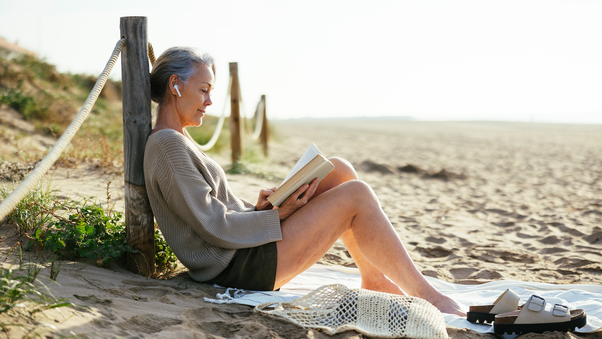 Woman sitting on beach reading book