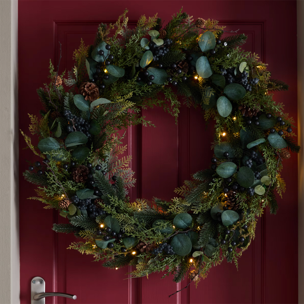 red front door with a large pre-lit wreath