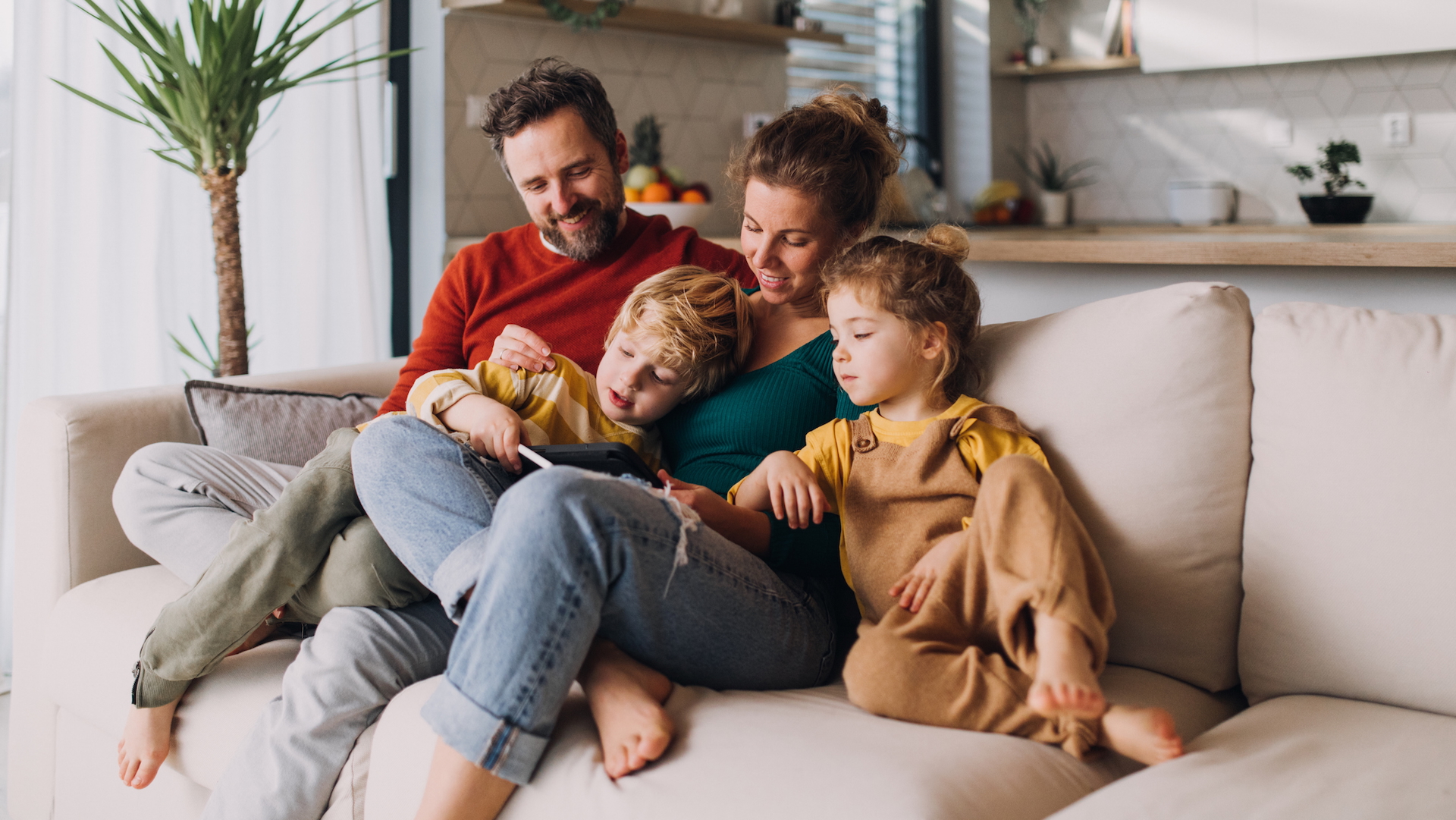 A man, woman and two children sit on a sofa