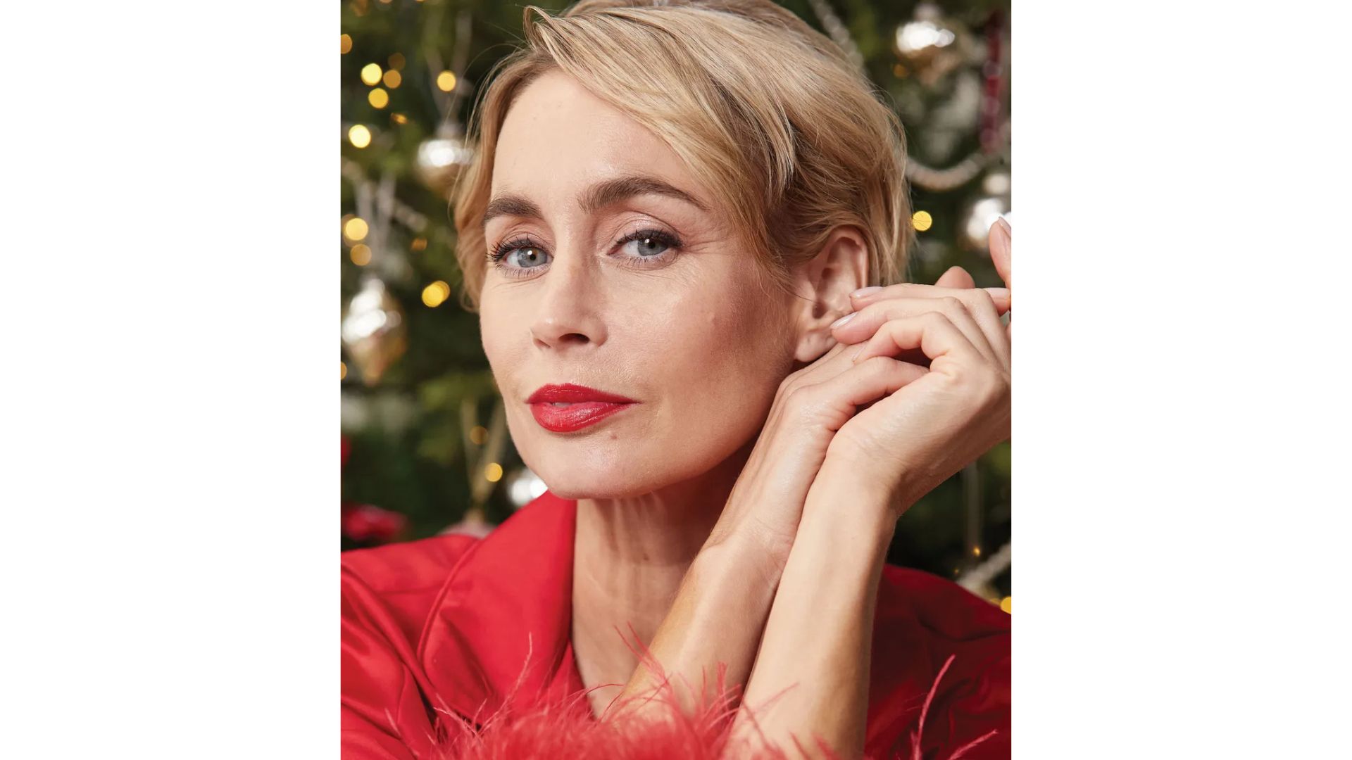 A woman with blonde short hair, wearing black eyeliner and red lipstick in a red top with fluffy sleeves