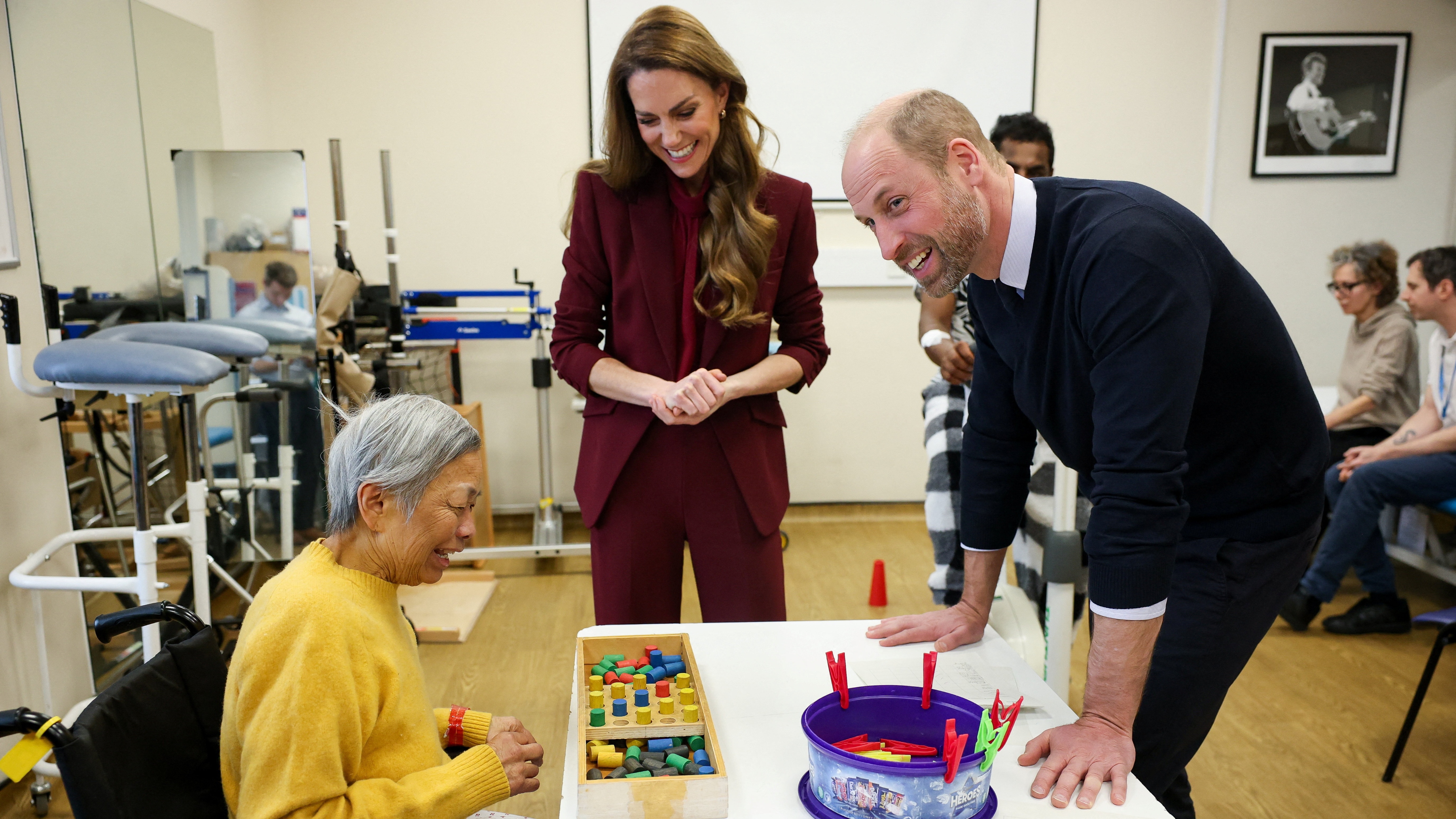 Prince William, Prince of Wales and Catherine, Princess of Wales speak to a patient at the therapy gym during a visit to Charing Cross Hospital