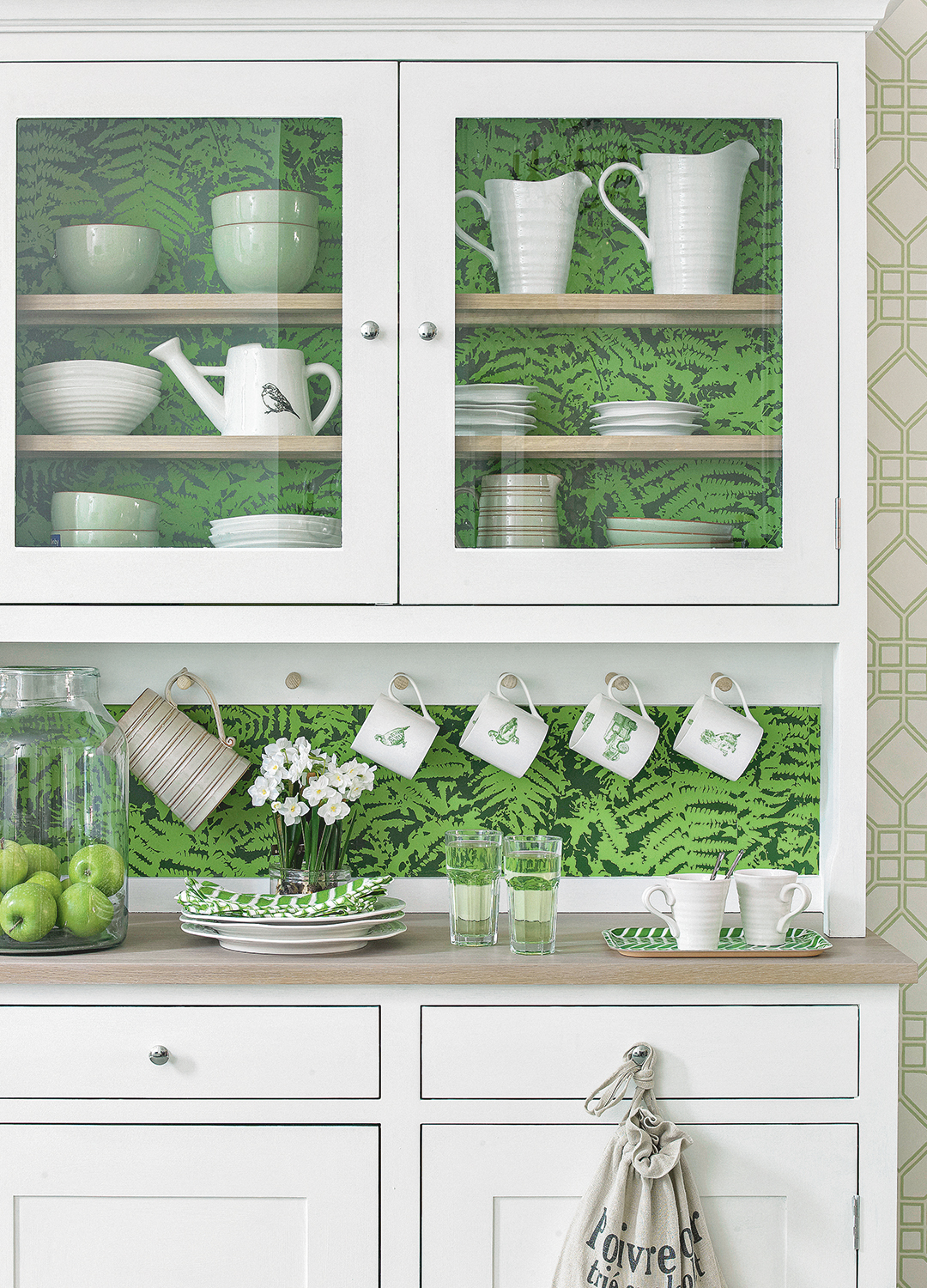 White display cabinet with green leaf pattern background with crockery