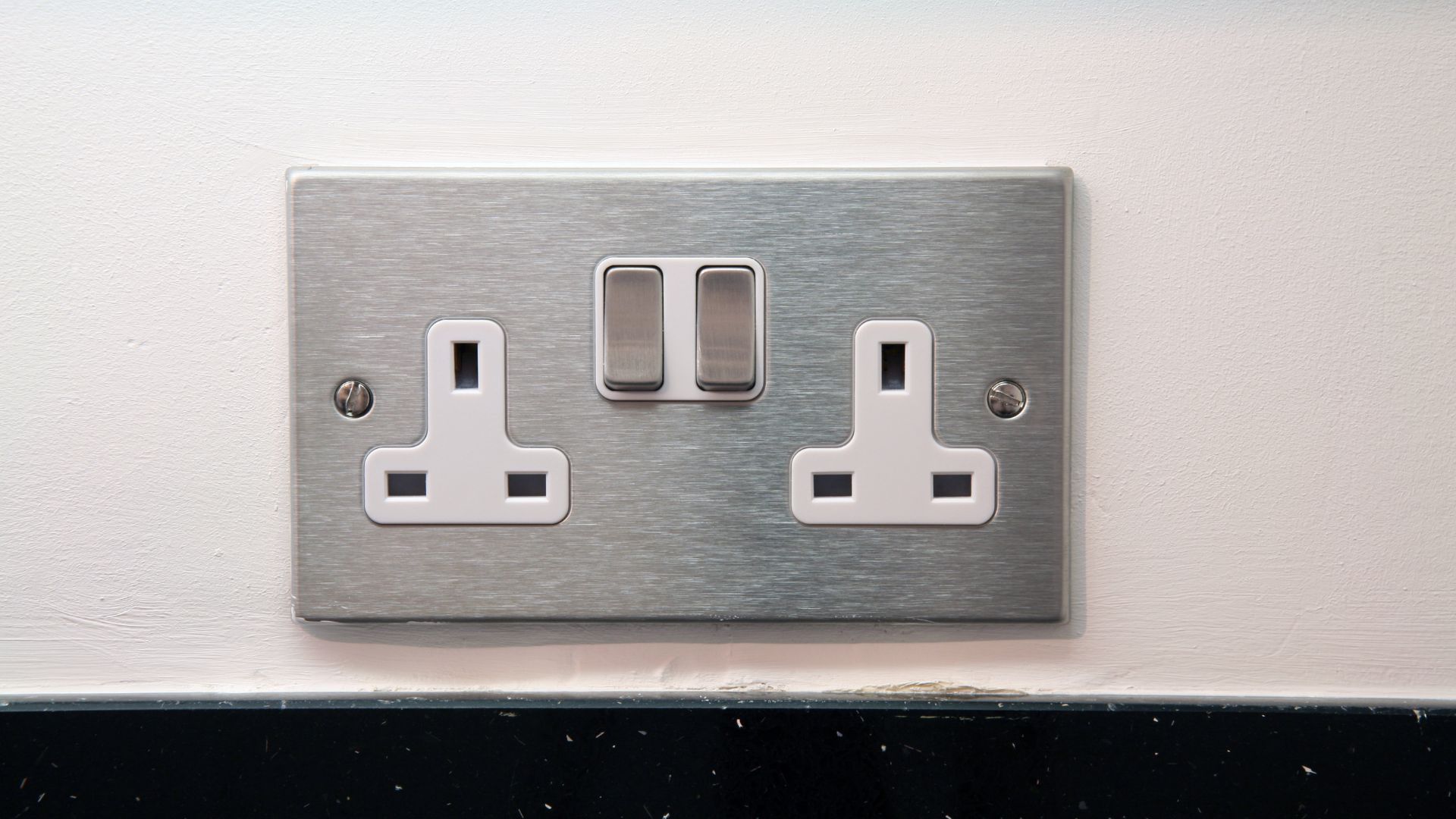 Stylish UK Plug Socket of brushed steel above granite kitchen surface