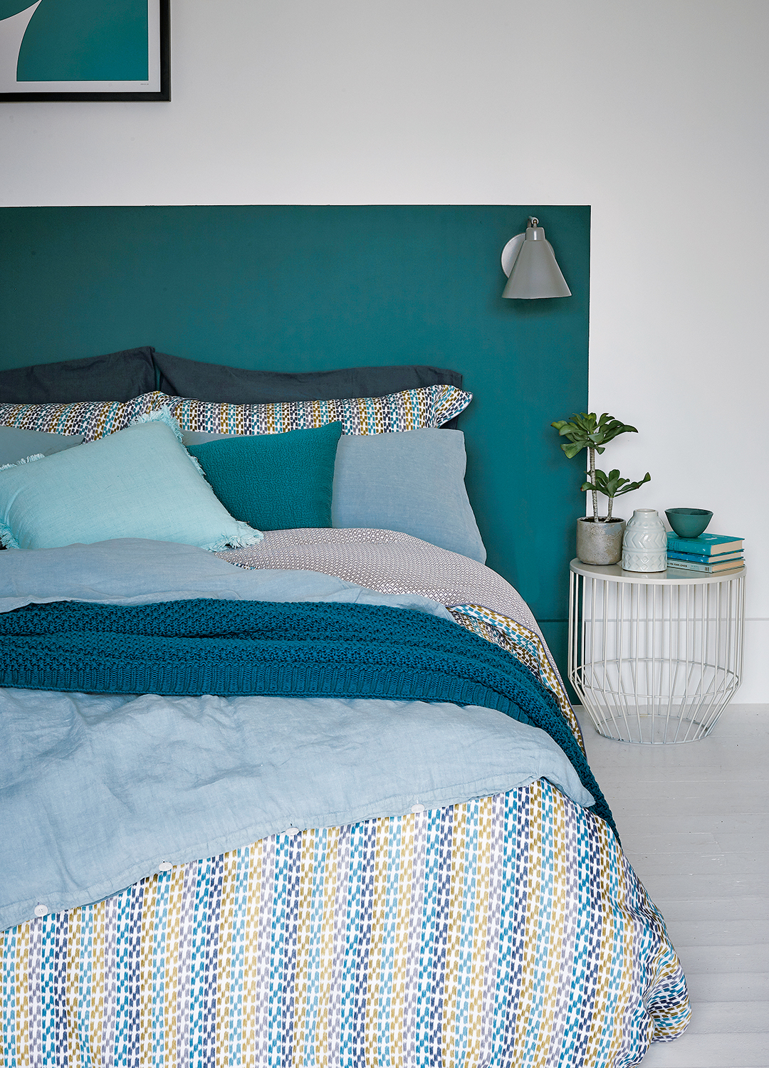 White bedroom with a headboard painted on teh wall in teal