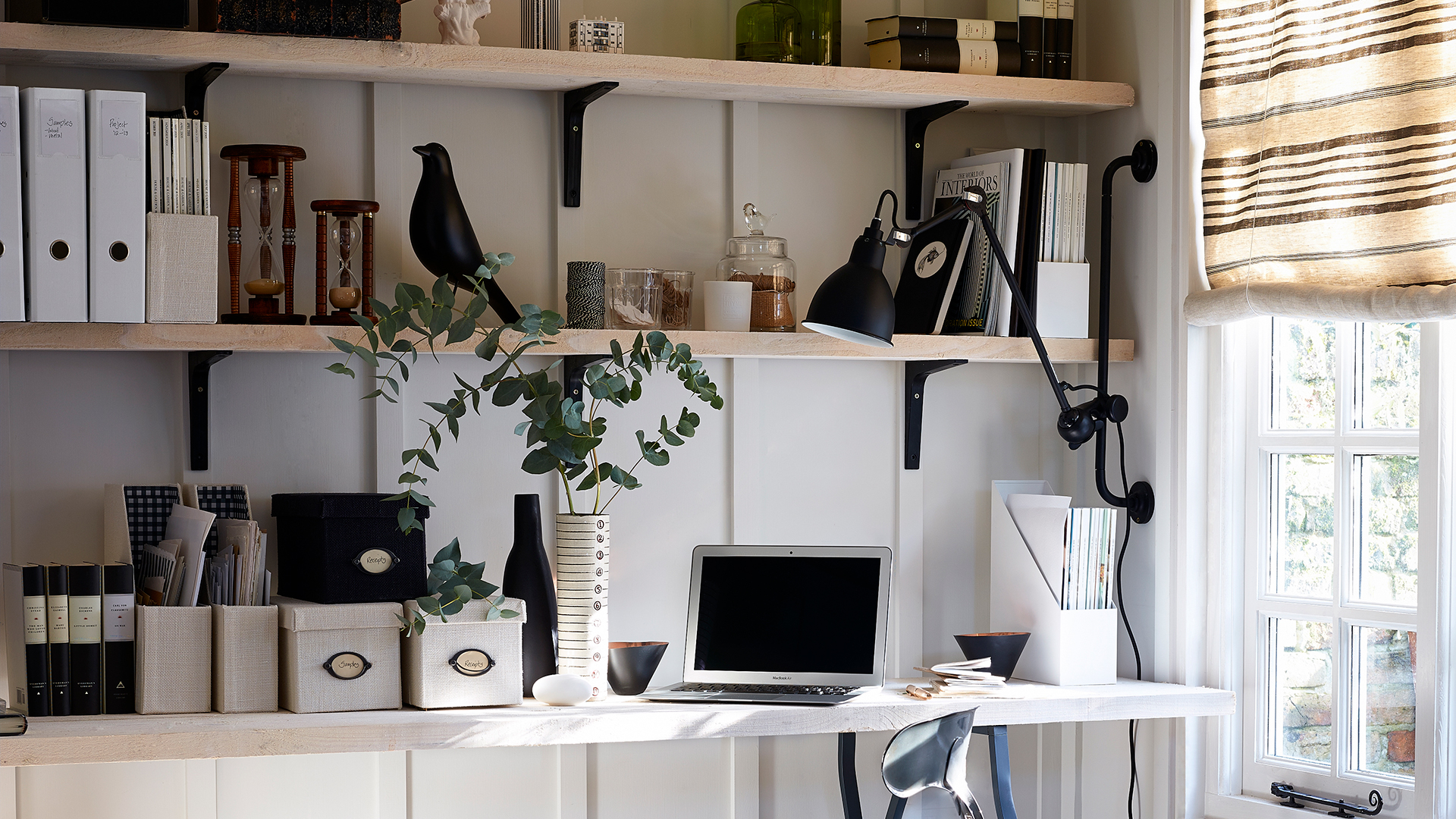 Home office with a monochrome colour scheme with a laptop and box files