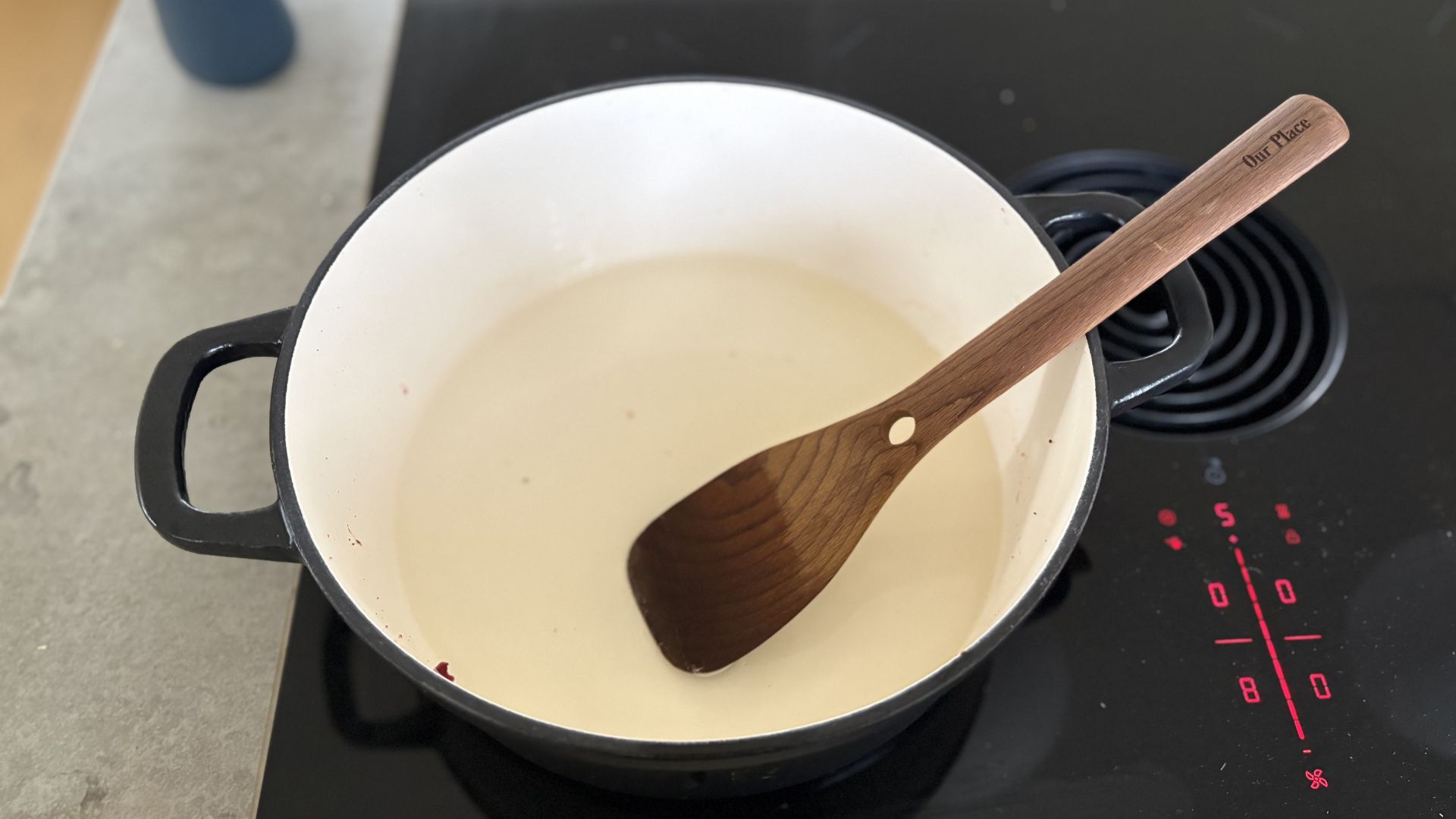 A stage of cleaning a burnt cast iron casserole dish on a hob